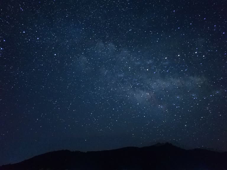 山脉上繁星点点的夜空,山下有帐篷