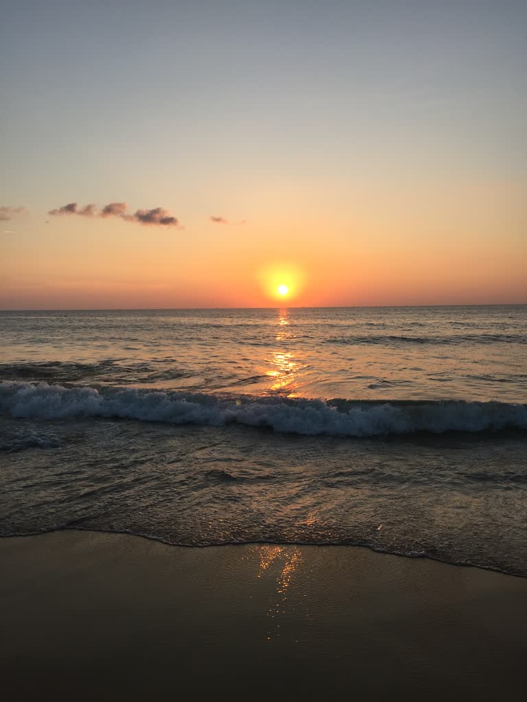 太阳落在海洋和海滩的地平线上